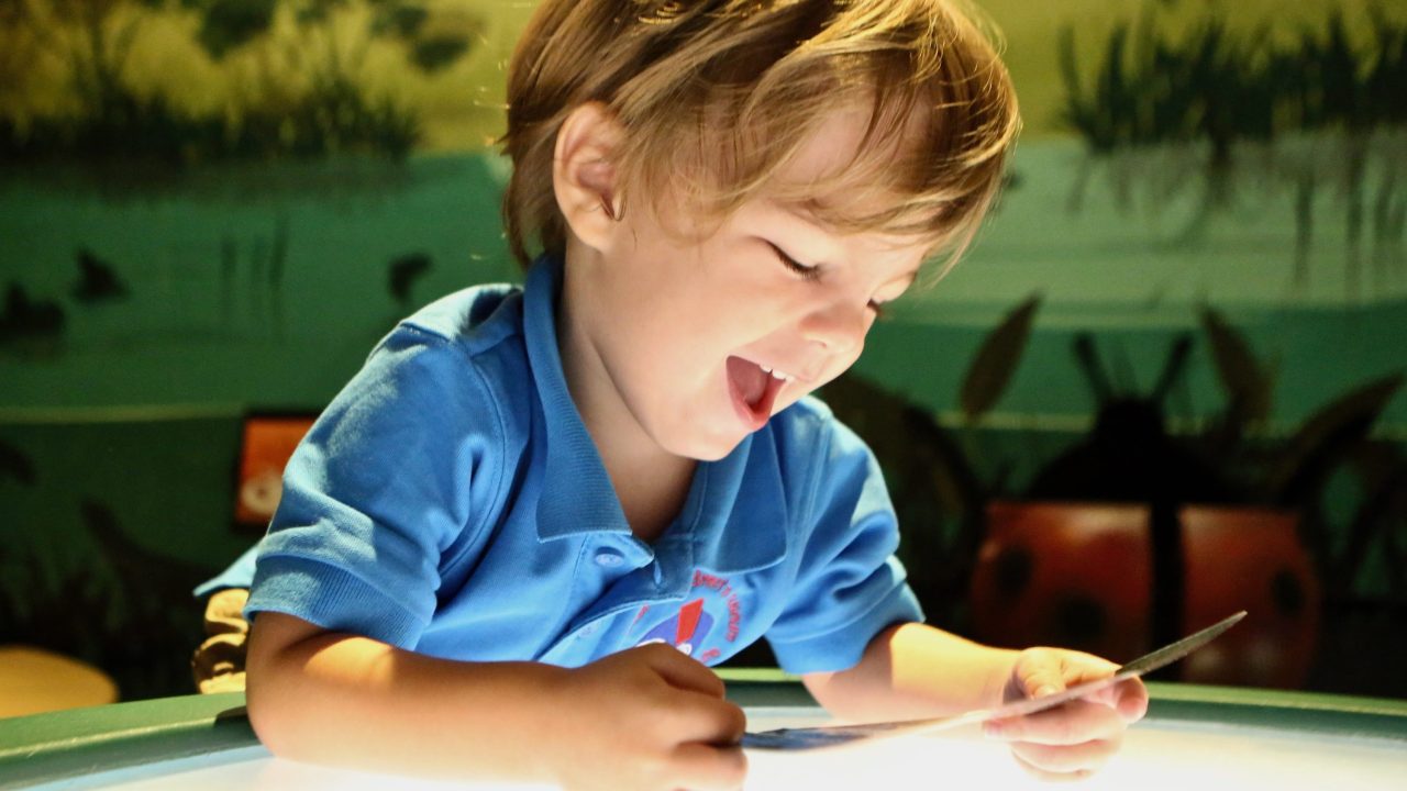 A child smiling while looking at a piece of paper